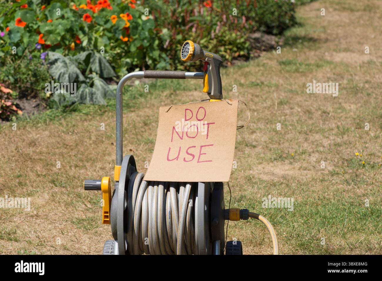 cartello di avvertenza divieto tubo flessibile, non utilizzare, avvolgitubo, mancanza di acqua a causa della siccità estate secca, erba marrone essiccata, vietato Foto Stock
