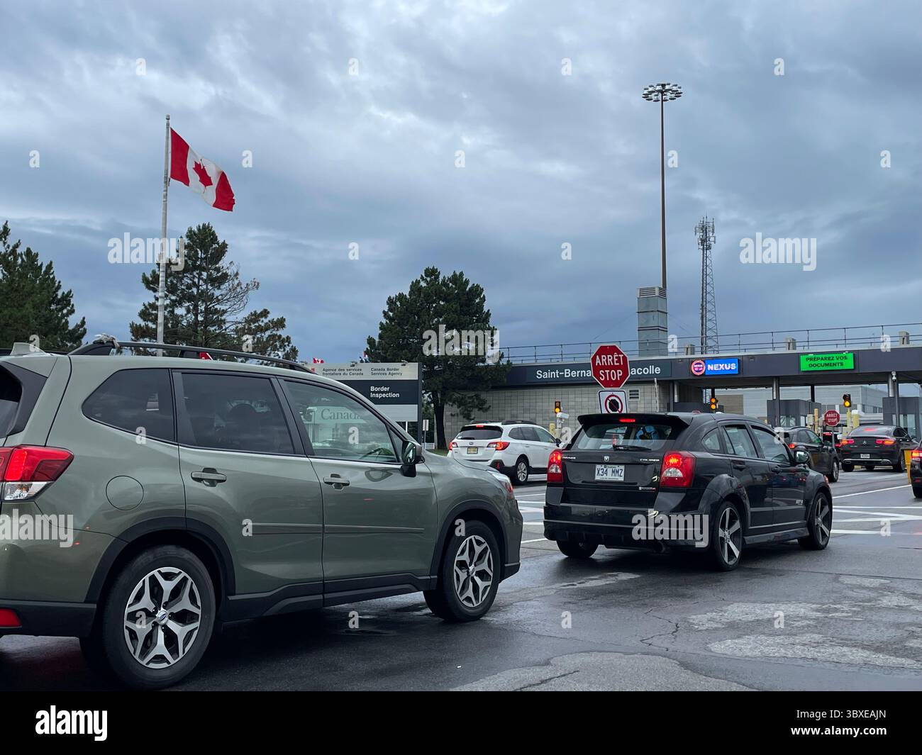 Una bandiera canadese sventola appena oltre il confine con gli Stati Uniti mentre le auto si dirigono verso l'agente doganale Foto Stock