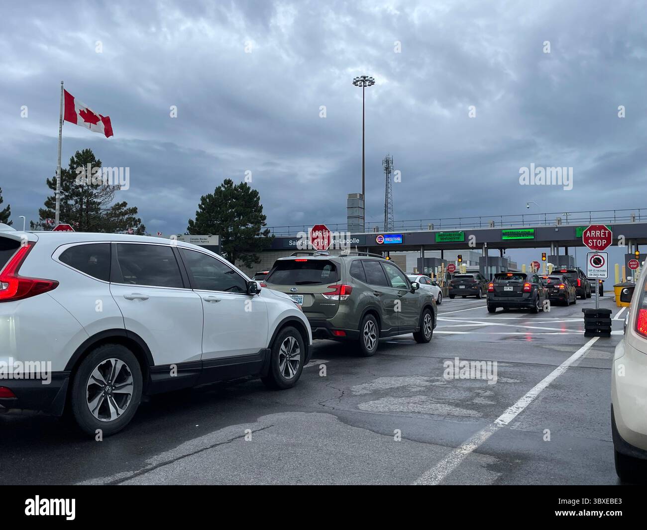 Una lunga fila di automobili attende e si avvicina all'agente doganale e al passaggio di frontiera in Canada Foto Stock