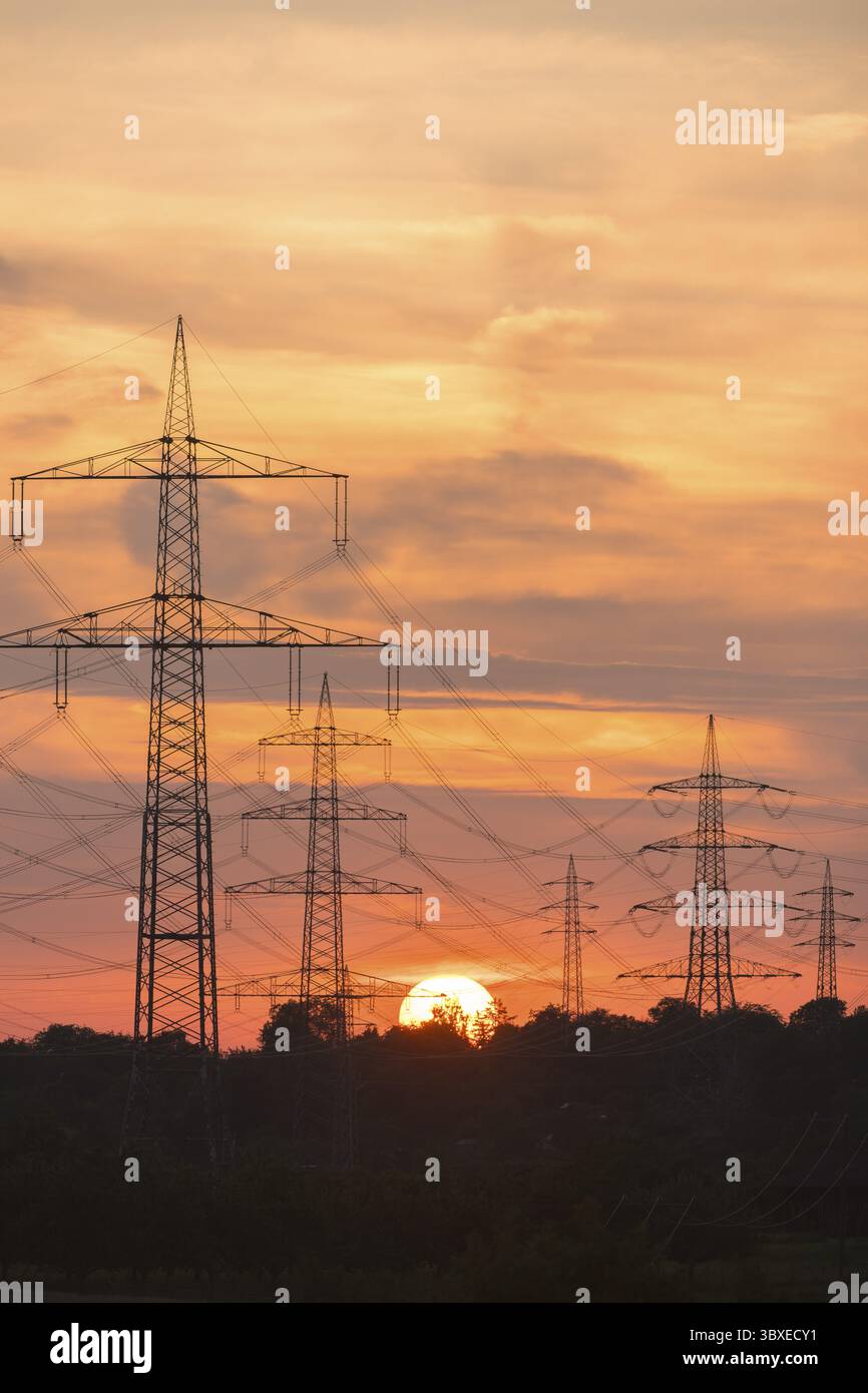 Linee elettriche ad alta tensione al tramonto con un intenso cielo arancione, Waiblingen, Baden-Wuerttemberg, Germania Foto Stock