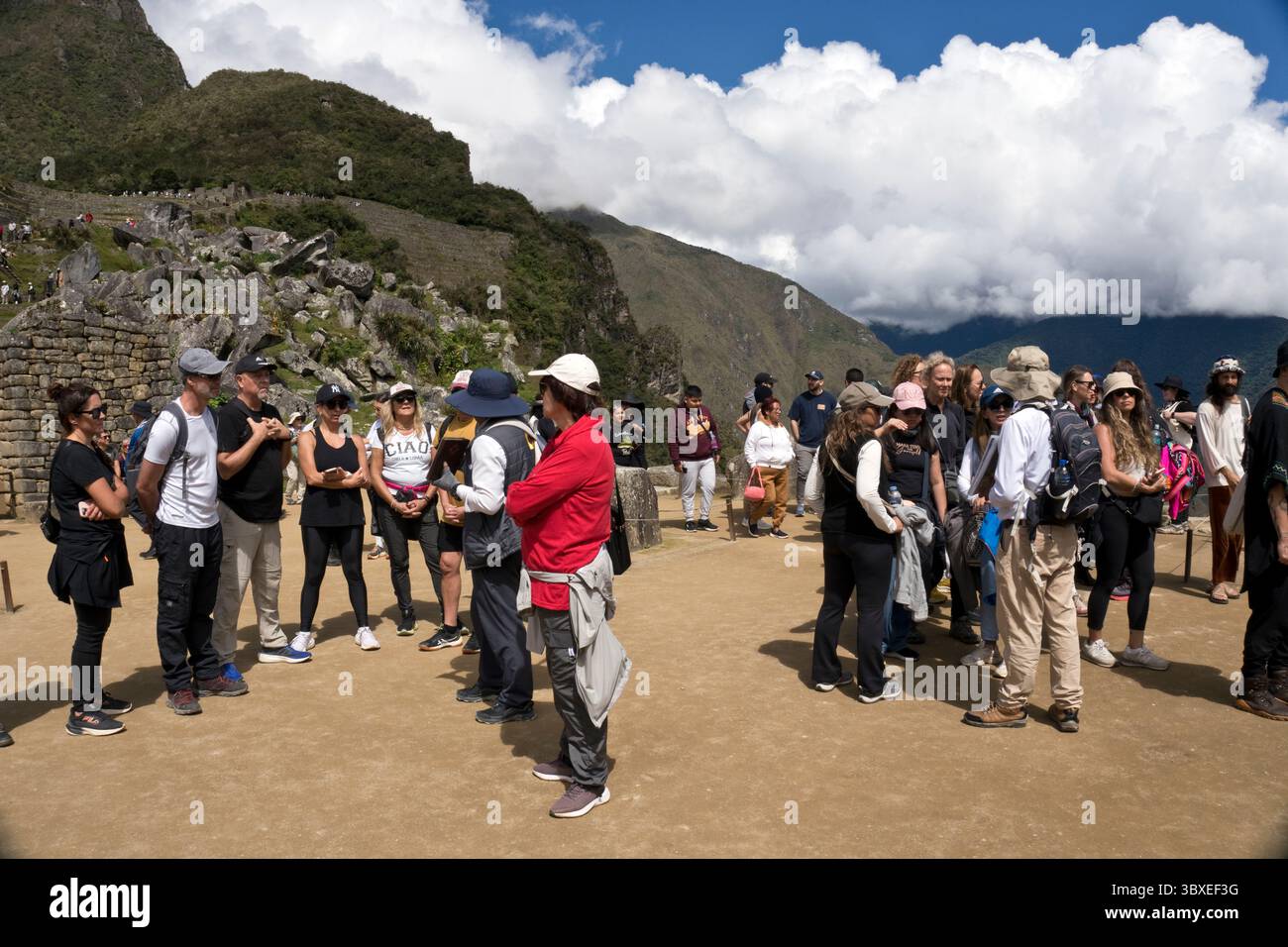 I gruppi del tour ascoltano le guide nella piazza sacra di Machu Picchu, la città inca del XV secolo in Perù. Foto Stock
