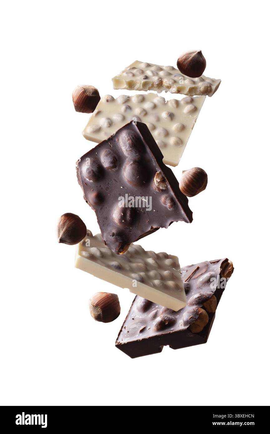 Pezzi di cioccolato fondente e bianco con nocciole girano su uno sfondo bianco Foto Stock