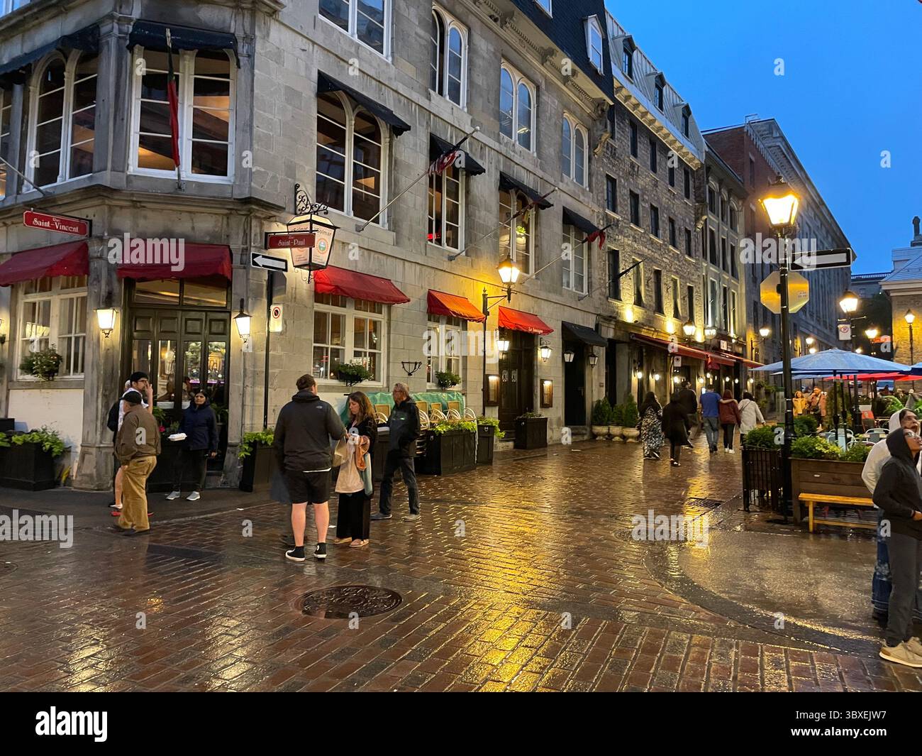 Le strade acciottolate della vecchia Montreal riflettono le luci dei caffè e delle boutique in una serata estiva Foto Stock