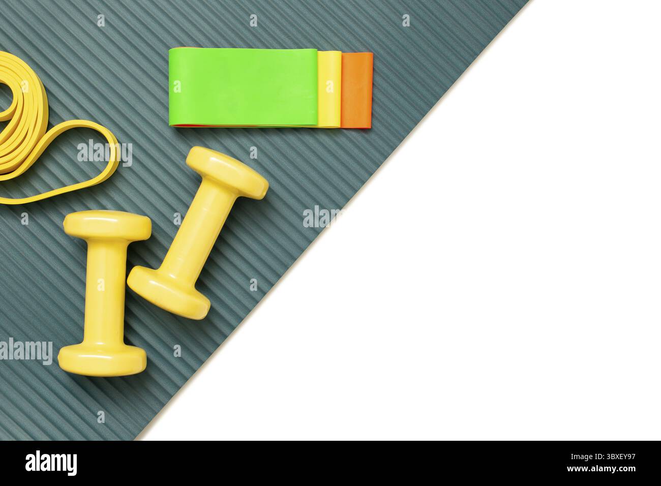 Set sportivo Flat View: Manubri e un set di fasce elastiche multicolore di diversi colori per il fitness su un tappetino sportivo e uno sfondo bianco diagon Foto Stock