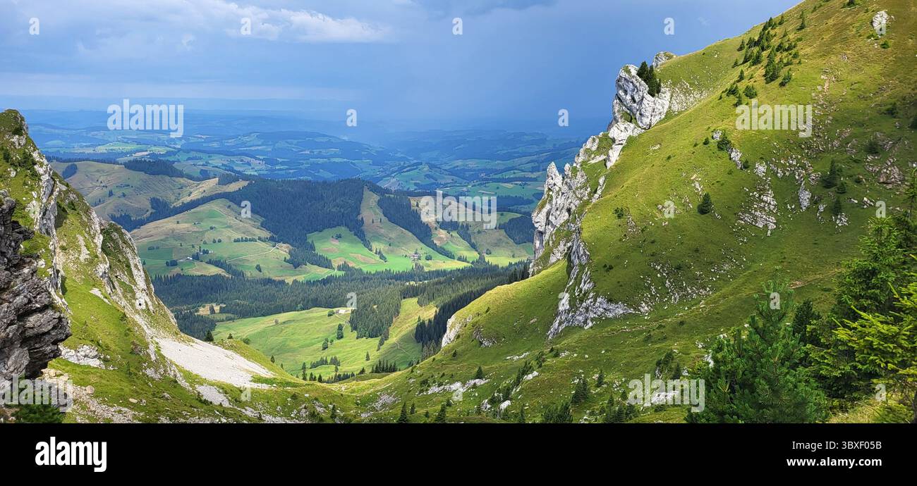 Paesaggio montano con prati verdi e vista sulla pianura dietro la sella delle Alpi svizzere Foto Stock
