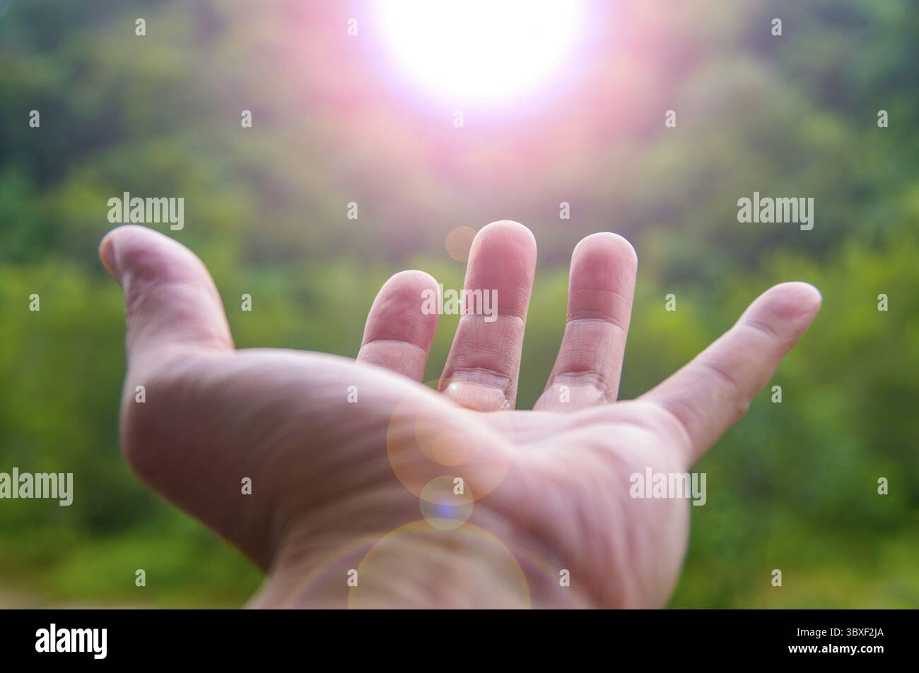 Mano che raggiunge una luce brillante che rappresenta la benedizione. Idee per spazi di testo per messaggi di ispirazione Foto Stock