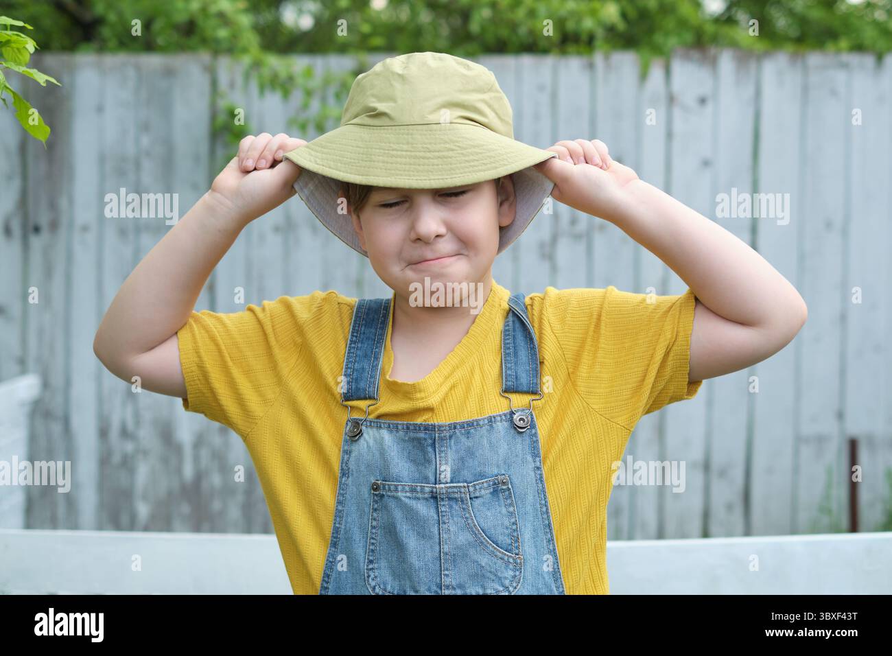 Immagine giocosa di un ragazzo vestito con una T-shirt gialla e una tuta in denim, la sua espressione gioiosa riflette l'emozione di impegnarsi in giochi divertenti e di Foto Stock