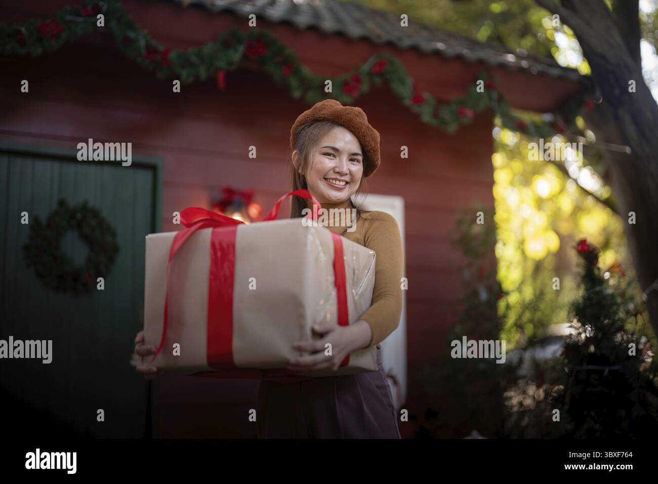 Uno spanditore per festività offre un regalo di Natale, incarnando lo spirito gioioso della stagione natalizia Foto Stock