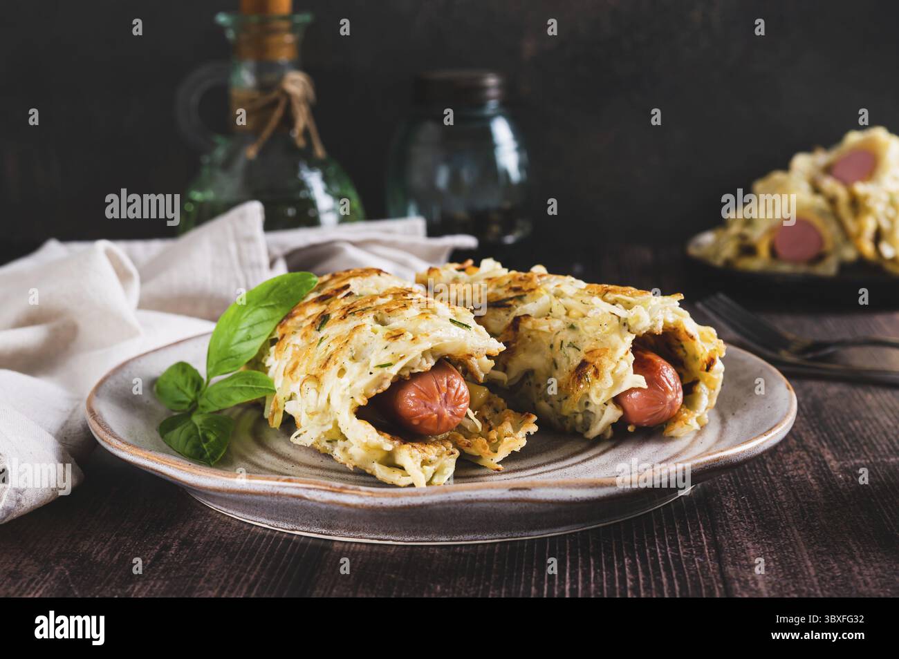Cibo, salsicce avvolte in frittelle di cavolo grattugiate su un piatto su un tavolo Foto Stock
