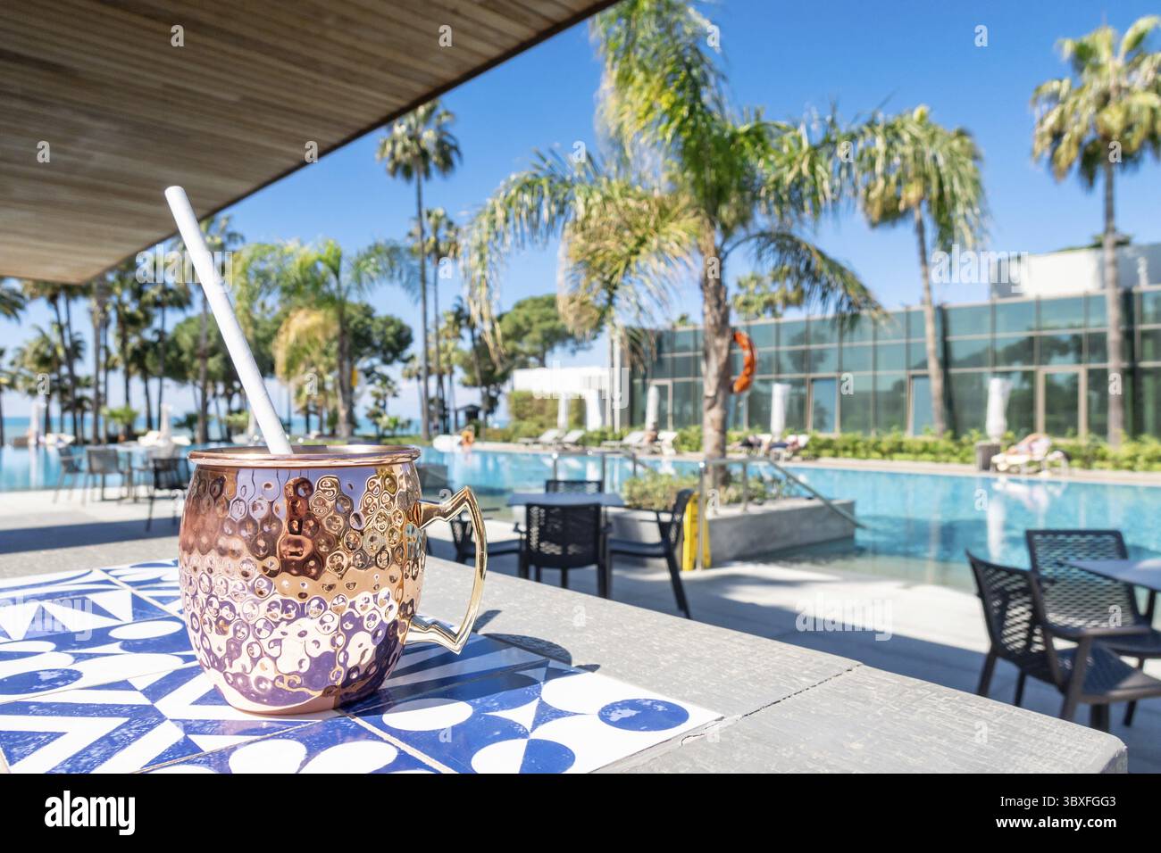 Cocktail mulo fresco di Mosca con ghiaccio, lime e foglie di menta in una tazza di rame in piscina. Drink rinfrescante per vacanze di lusso. Concetto di vacanza estiva Foto Stock