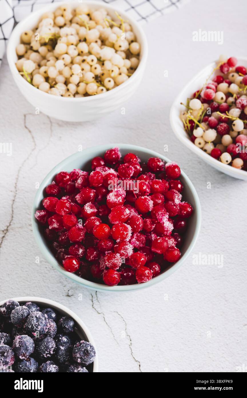 Cibo, viburno congelato in un recipiente e altre bacche sul tavolo vista verticale Foto Stock