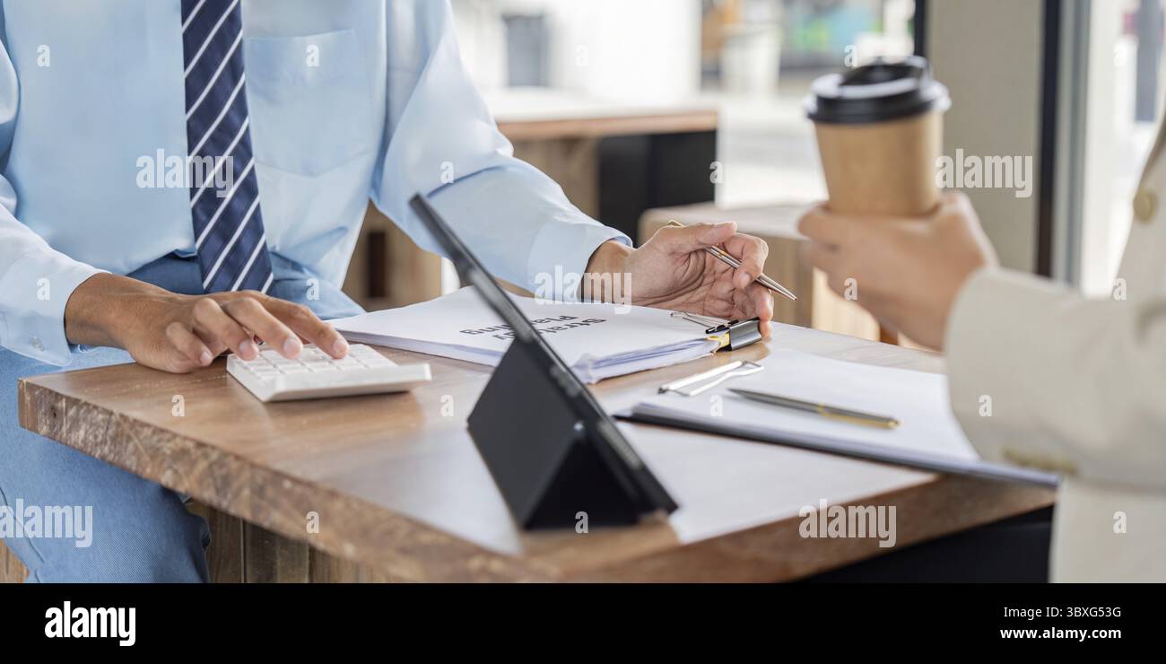 Il team aziendale esamina i report finanziari con una calcolatrice e un tablet in un bar, migliorando il processo decisionale strategico con la tecnologia Foto Stock