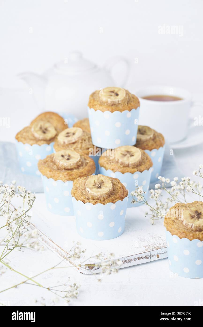 Muffin alla banana, cupcakes in carta blu, vista laterale, vertigini. Colazione al mattino su un tavolo bianco in cemento Foto Stock