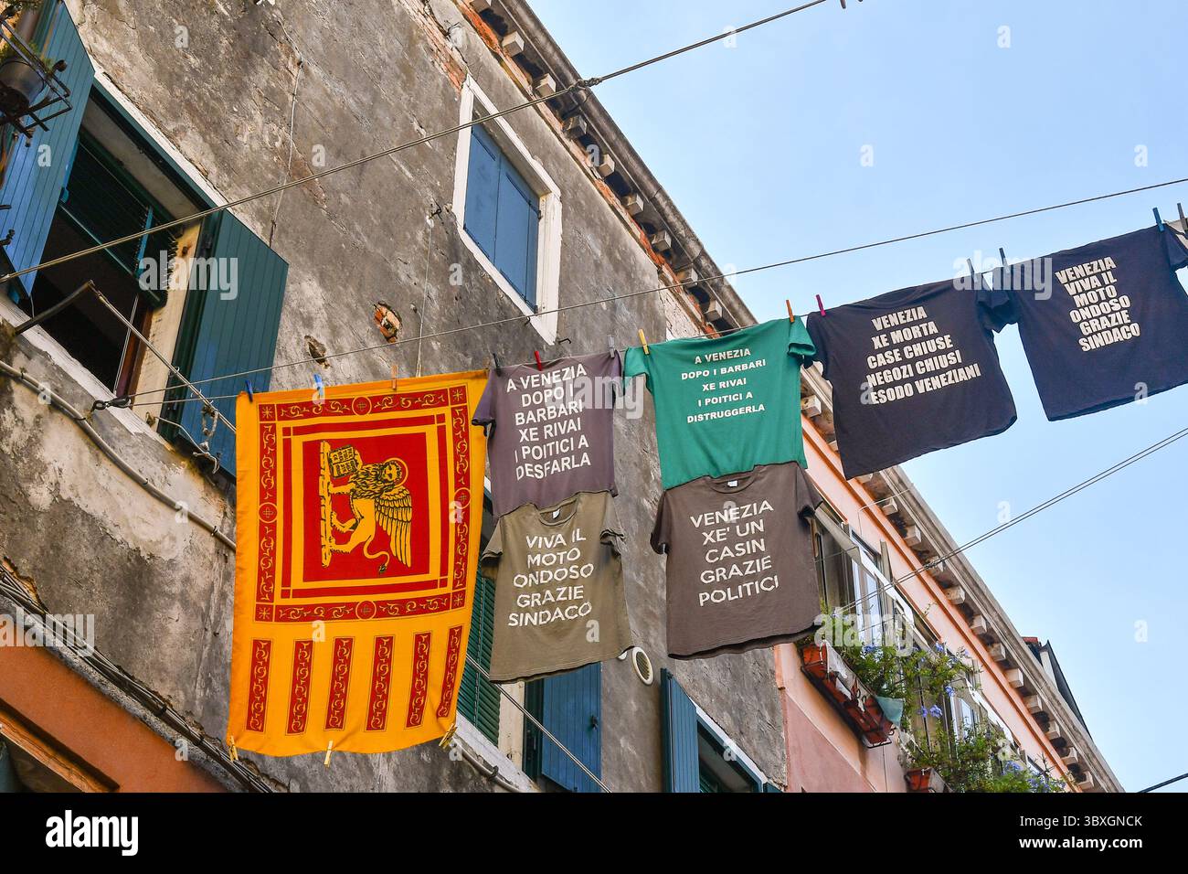 Vista a basso angolo della maglietta di protesta contro i politici veneziani, appesa a clothesline in Corte nuova, quartiere Castello, Venezia, Veneto, Italia Foto Stock