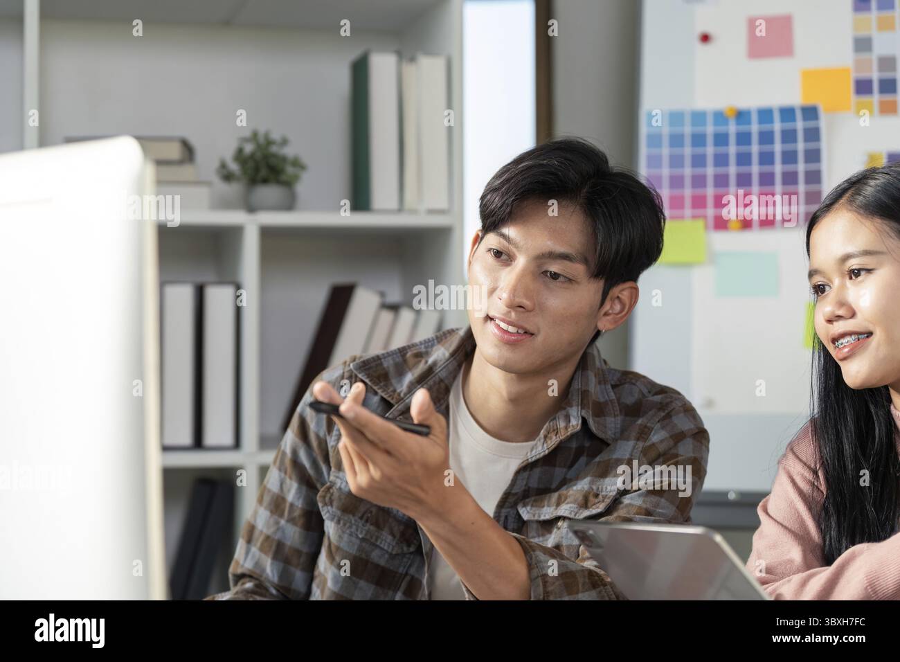 Collaborazione tra team nella progettazione grafica spazio ufficio interazione digitale ambiente creativo punto di vista coinvolgente Foto Stock