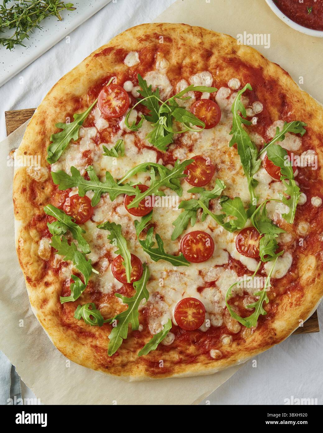 Pasta italiana casalinga per pizza margherita condita con salsa per pizza di pomodori in scatola, mozzarella e rucola, verticale Foto Stock