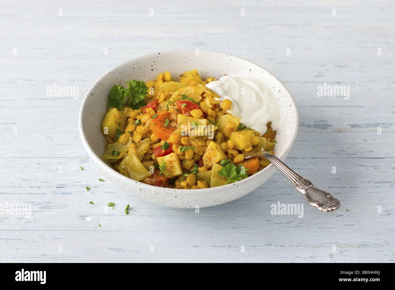 Cibo, stufato di verdure con piselli e curry con yogurt cosparso di prezzemolo su sfondo azzurro, cucina indiana Foto Stock
