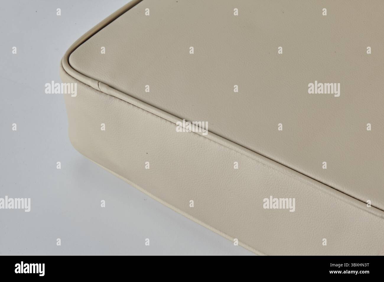 Primo piano di un cuscino del sedile in pelle beige, evidenziando i dettagli delle cuciture e la consistenza liscia Foto Stock