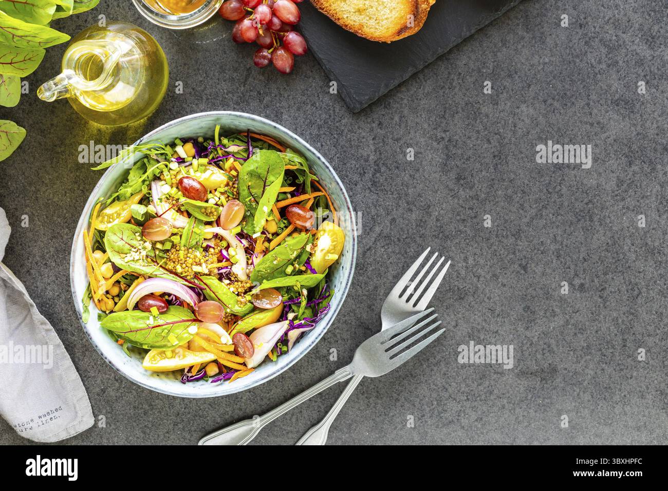 Cibo, verdura fresca e Macedonia di frutta in un piatto su sfondo di pietra nera Foto Stock