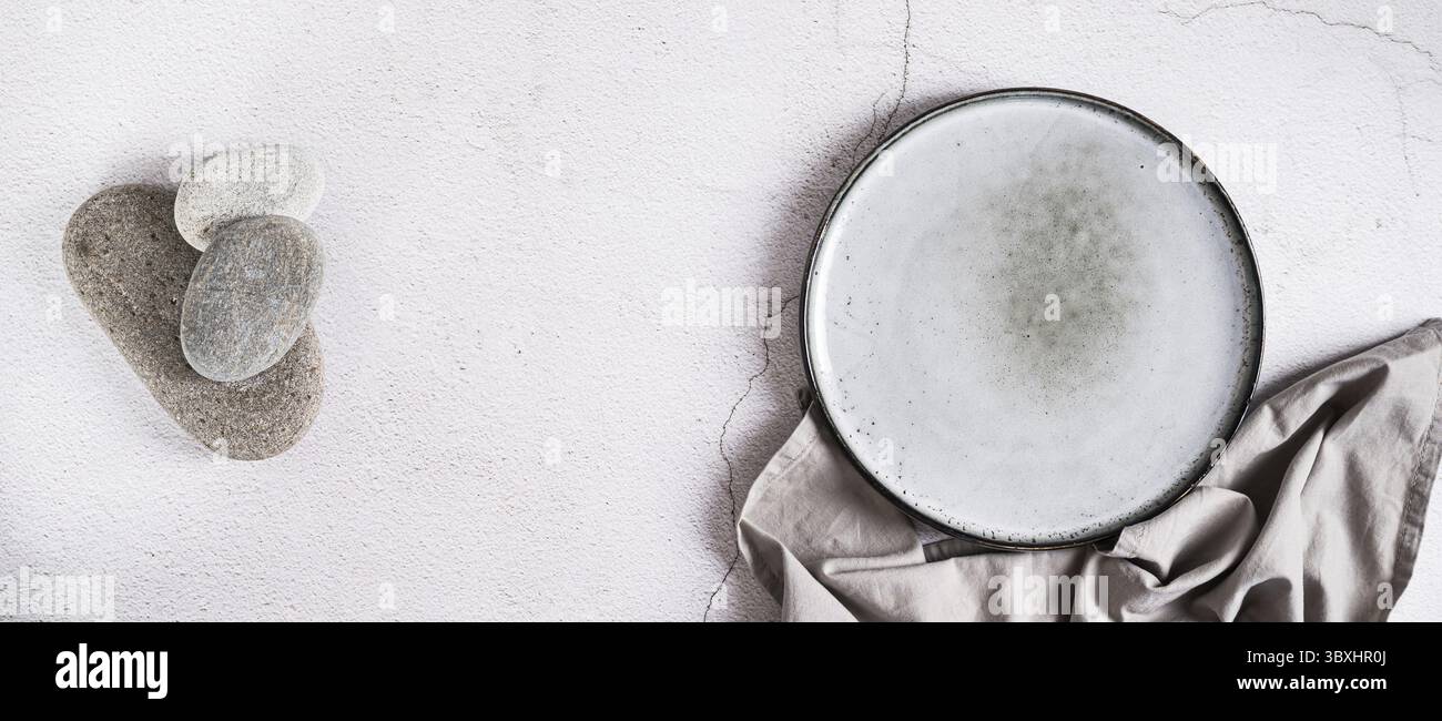 Cibo, piastra in ceramica vuota, pietre e tovagliolo su sfondo grigio banner Web con vista dall'alto Foto Stock