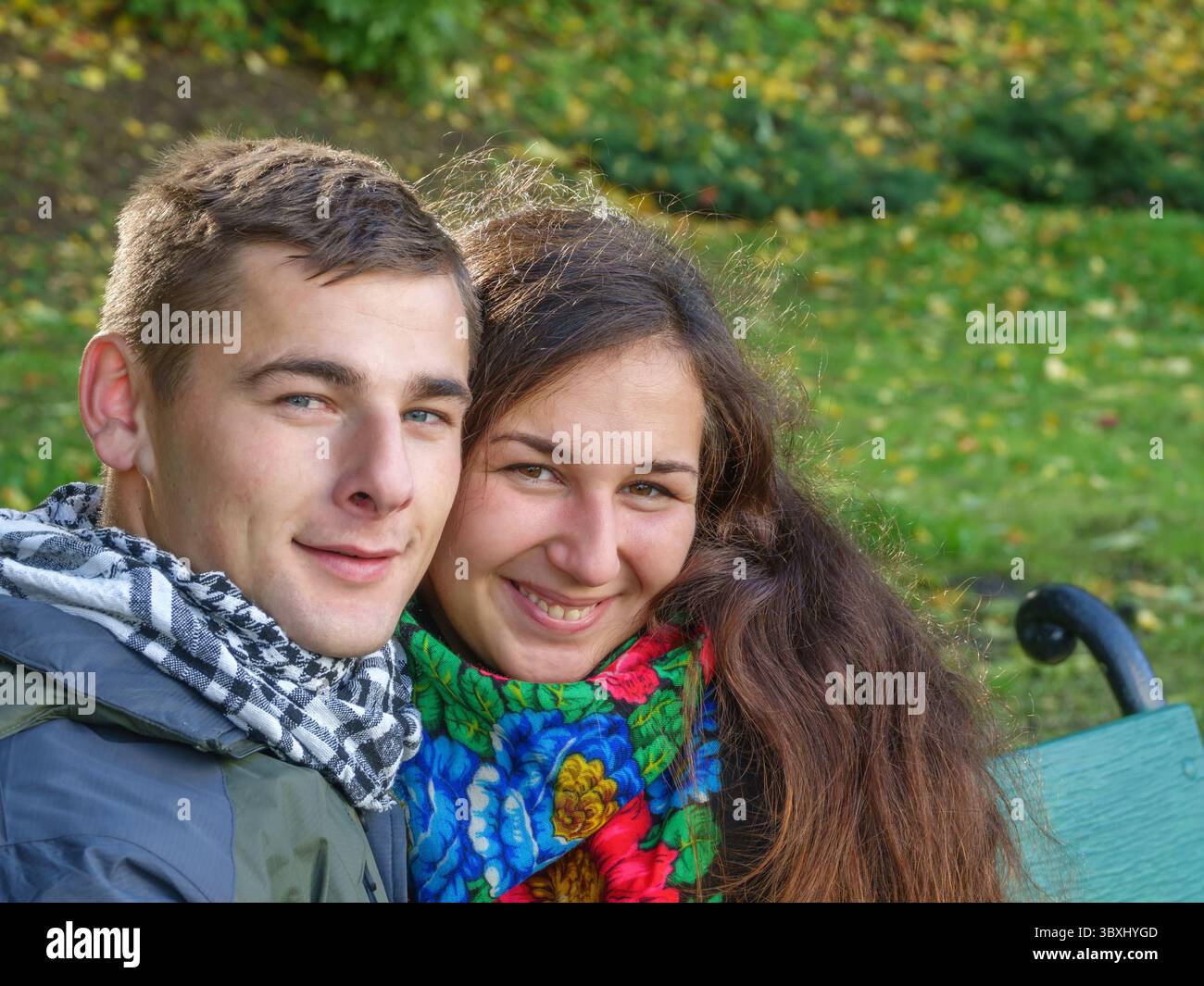 Innamorato ragazzo e ragazza su una data tratta su una panchina in un parco di autunno Foto Stock