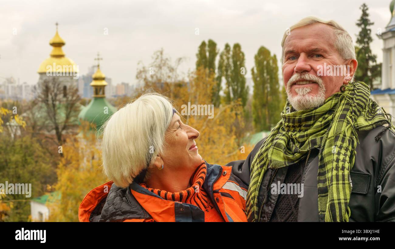 Felice bella anziana coppia sposata con capelli grigi sullo sfondo di alberi autunnali con foglie gialle Foto Stock