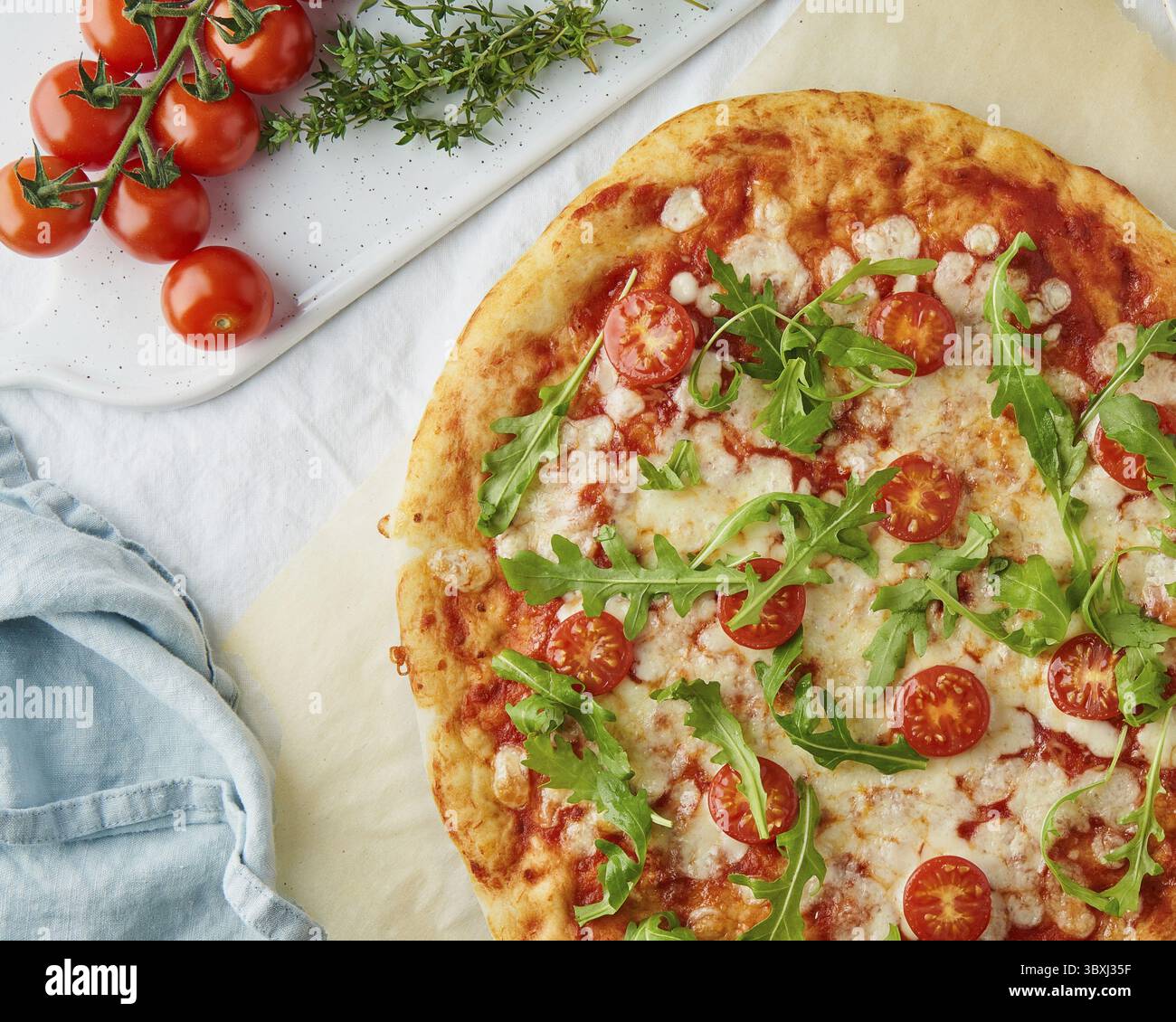 Parte di una margherita rustica di pasta fatta in casa italiana condita con salsa per pizza di pomodori in scatola, mozzarella e rucola Foto Stock