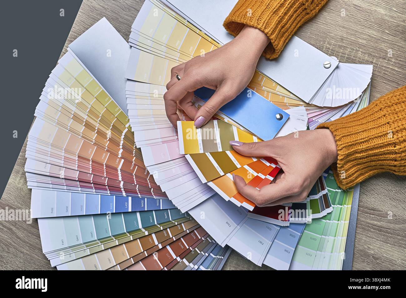 Ruota dei colori per la scelta del tono di vernice. Mani di una designer di interni che lavora con la tavolozza per scegliere i colori. Concetto di processo creativo. Confronto di o Foto Stock