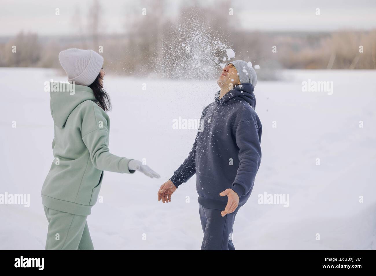 Coppia felice che gioca a partita invernale nella foresta all'aperto. Concetto di amore e tempo libero. Foto Stock