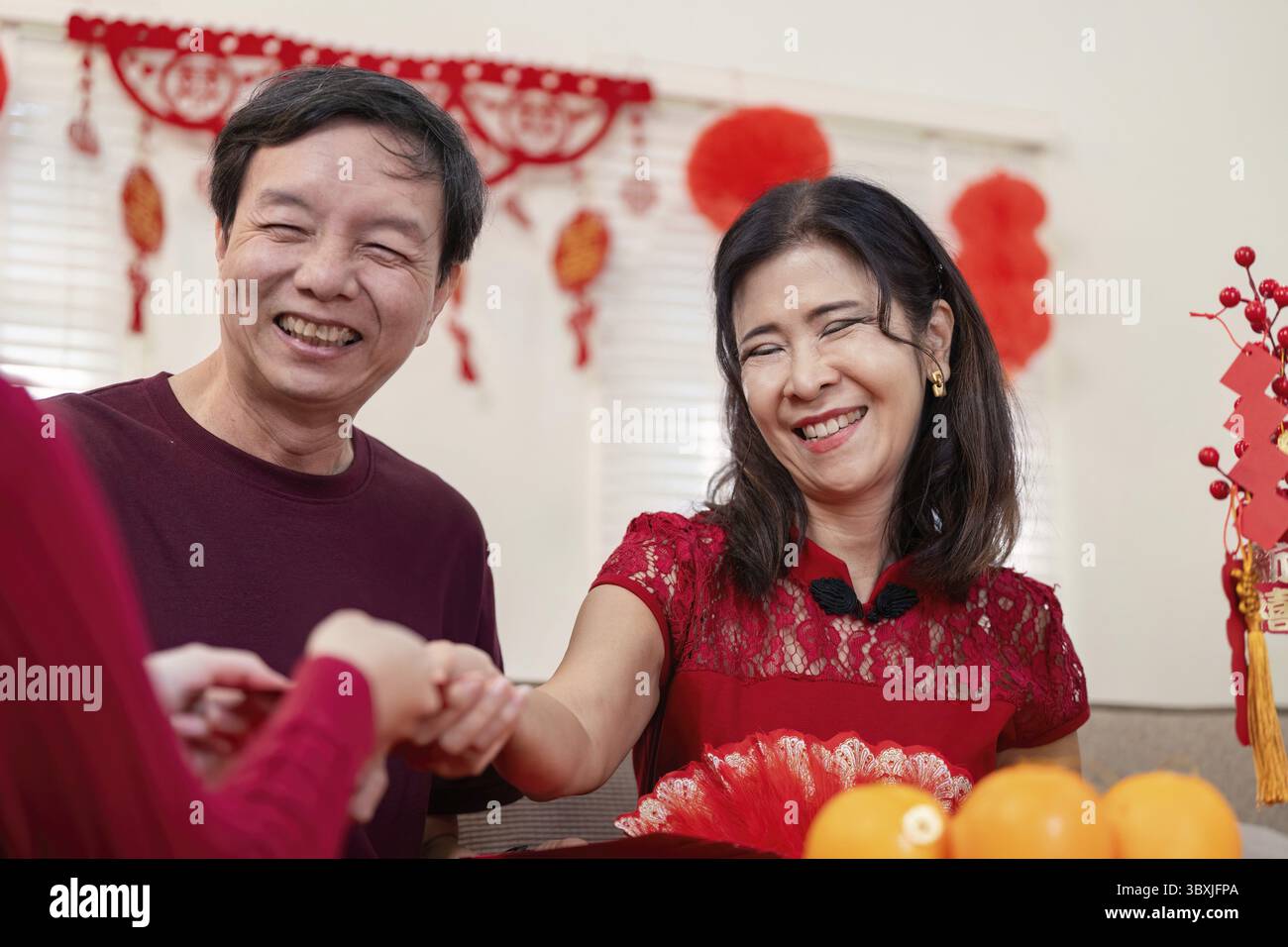 Una gioiosa riunione di famiglia che celebra il capodanno cinese che mette in evidenza l'amore tra i nonni e la loro nipote Foto Stock