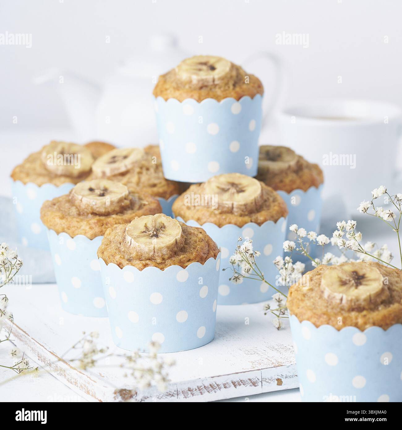 Muffin alla banana, cupcake in carta blu, vista laterale. Colazione al mattino su un tavolo bianco in cemento Foto Stock