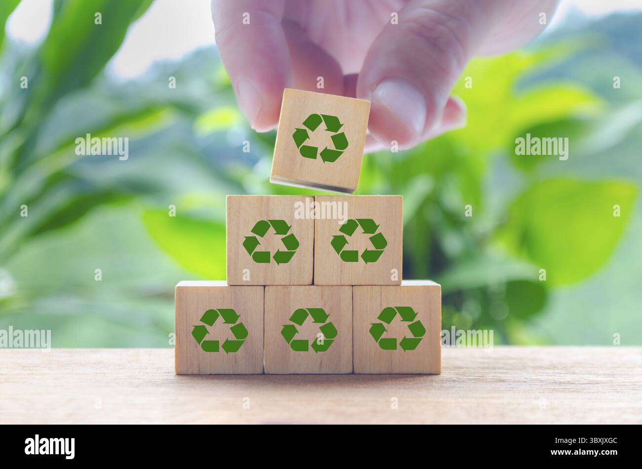 Ricicla i simboli su cubi di legno con sfondo naturale sfocato. Riciclare e preservare il concetto di natura Foto Stock