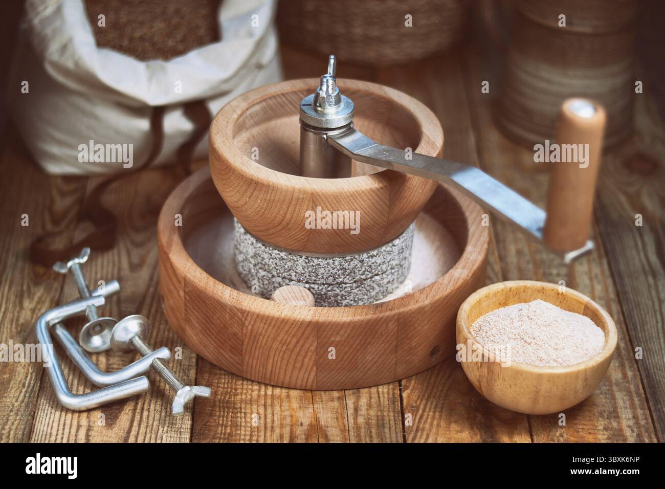 Smerigliatrice per cereali - Mulino manuale per smerigliatura manuale, su un tavolo di legno Foto Stock