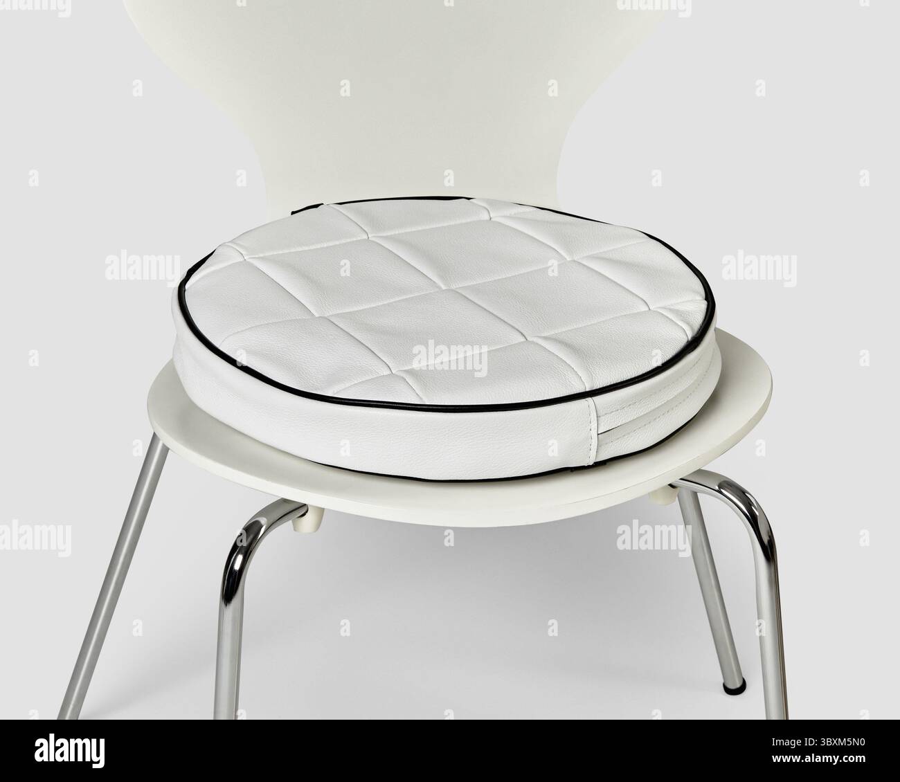 Il cuscino del sedile rotondo in ecopelle bianca con cuciture nere aggiunge comfort a una moderna sedia bianca, perfetta per migliorare la disposizione dei sedili Foto Stock