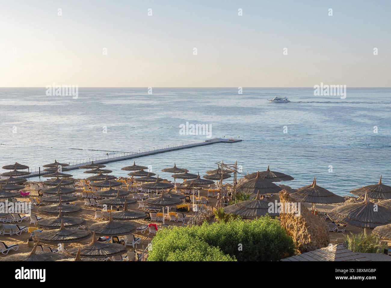Vista panoramica della spiaggia di Ras Umm El Sid. Splendida alba sul Mar Rosso con coste rocciose, spiaggia sabbiosa con ombrelloni e primi raggi di sole, Sharm El S. Foto Stock