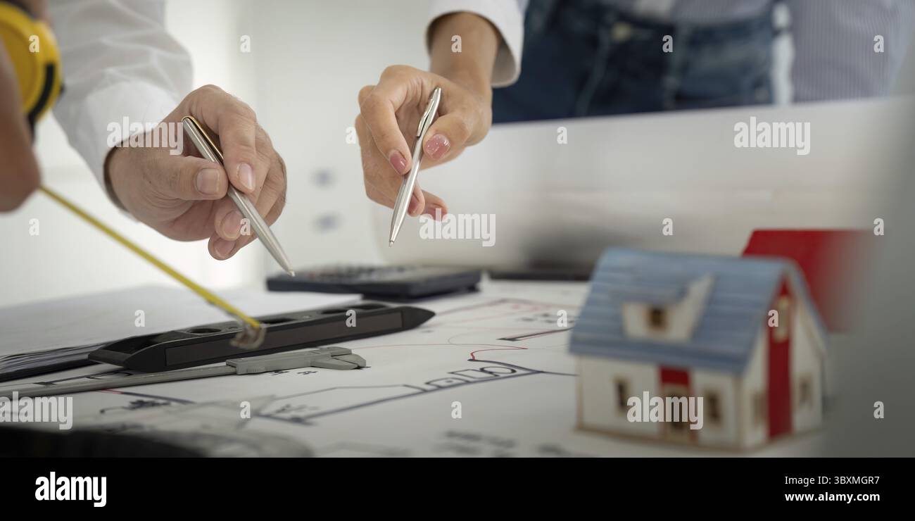 Una discussione collaborativa che si svolge tra i colleghi mentre esaminano i progetti e utilizzano strumenti per la pianificazione della costruzione, sottolineando il lavoro di squadra e. Foto Stock Una discussione collaborativa che si svolge tra i colleghi mentre esaminano i progetti e utilizzano strumenti per la pianificazione della costruzione, sottolineando il lavoro di squadra e. Foto Stock