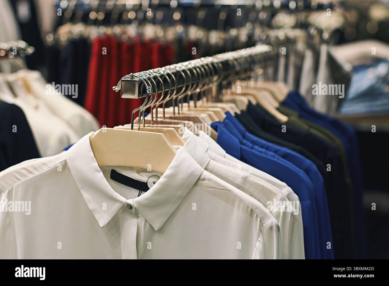Camicie da donna e camicette in bianco, blu, nero e altri colori su appendiabiti in un negozio di abbigliamento Foto Stock