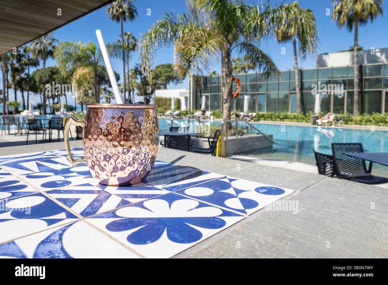 Cocktail mulo fresco di Mosca con ghiaccio, lime e foglie di menta in una tazza di rame in piscina. Drink rinfrescante per vacanze di lusso. Concetto di vacanza estiva Foto Stock