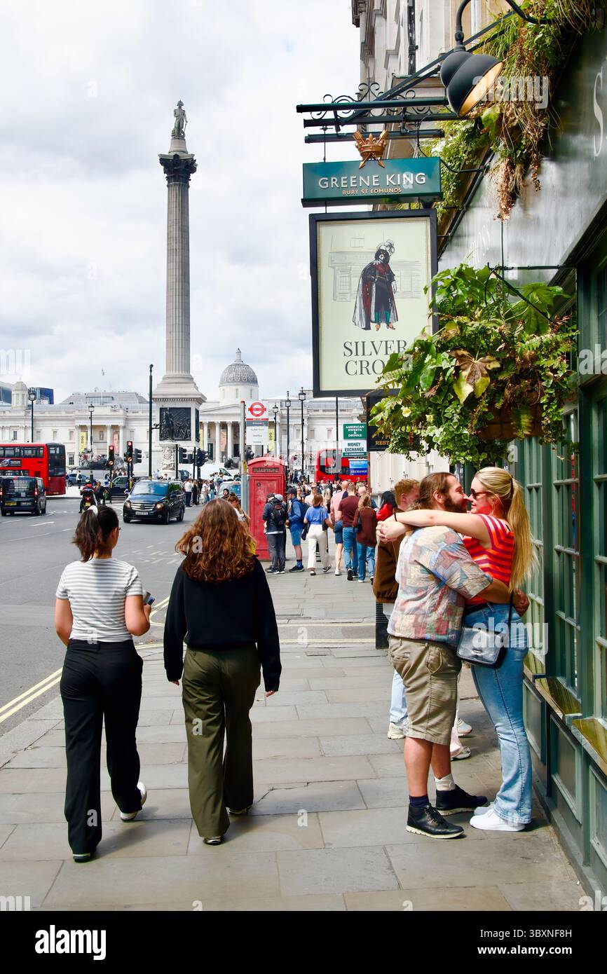 La coppia si trova all'esterno del pub Silver Cross vicino alla colonna di nelson e a Trafalgar Square Whitehall Londra Inghilterra Regno Unito Europa Foto Stock