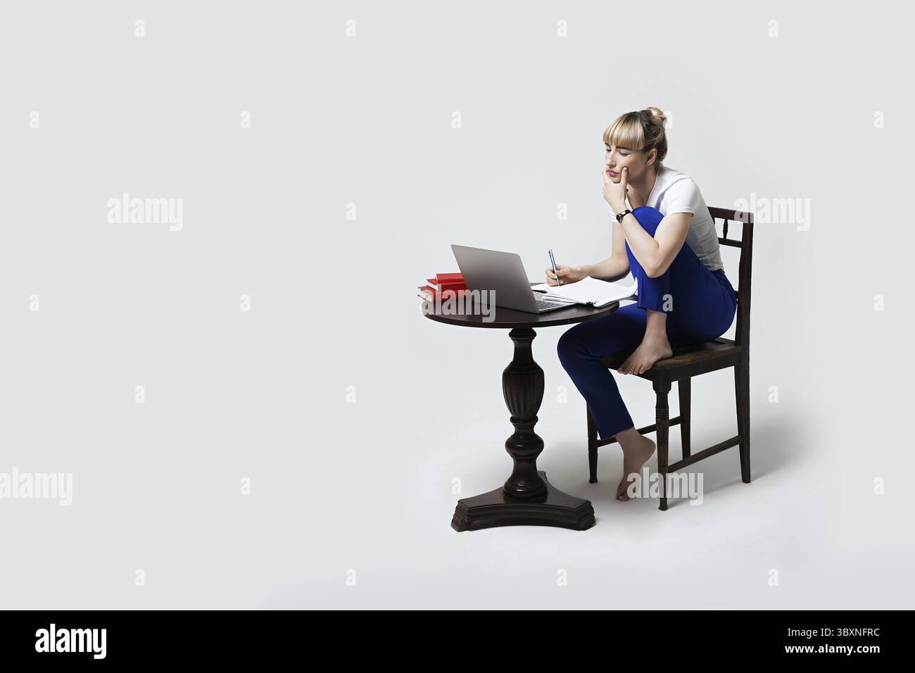 Giovane studentessa concentrata che lavora alla scrivania o studia in remoto online scrivendo appunti mentre guarda sullo schermo del notebook. Apprendimento a distanza o rem Foto Stock