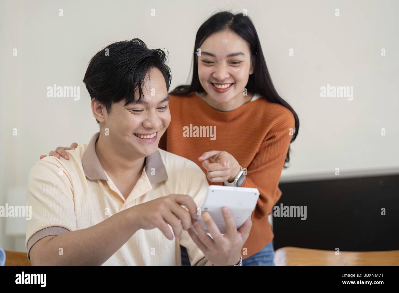 Una coppia esamina con piacere i documenti finanziari e le fatture, migliorando le proprie capacità di budget e il lavoro di squadra nella gestione delle finanze Foto Stock