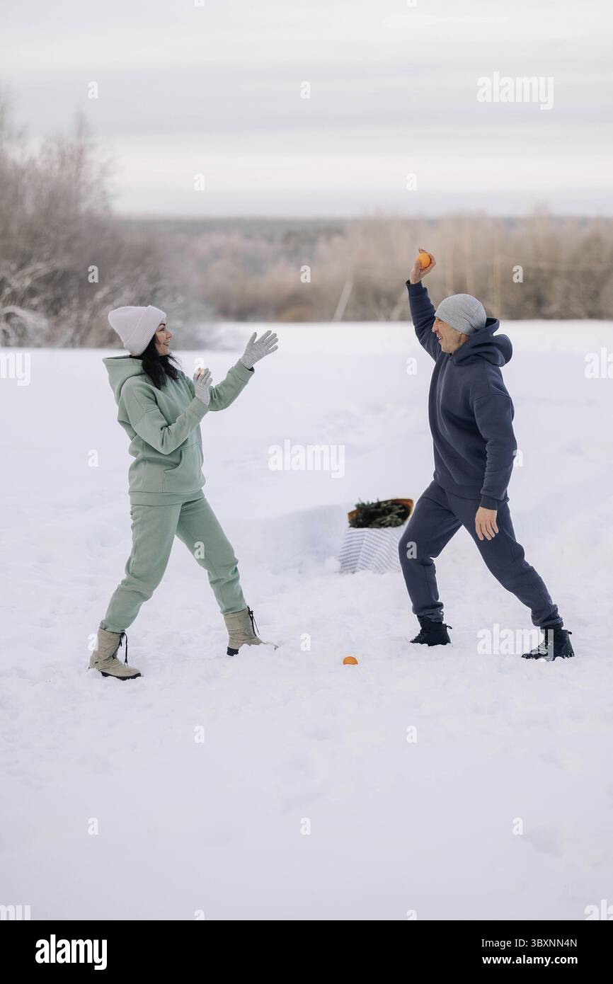 Coppia felice che gioca a partita invernale nella foresta all'aperto. Concetto di amore e tempo libero. Foto Stock