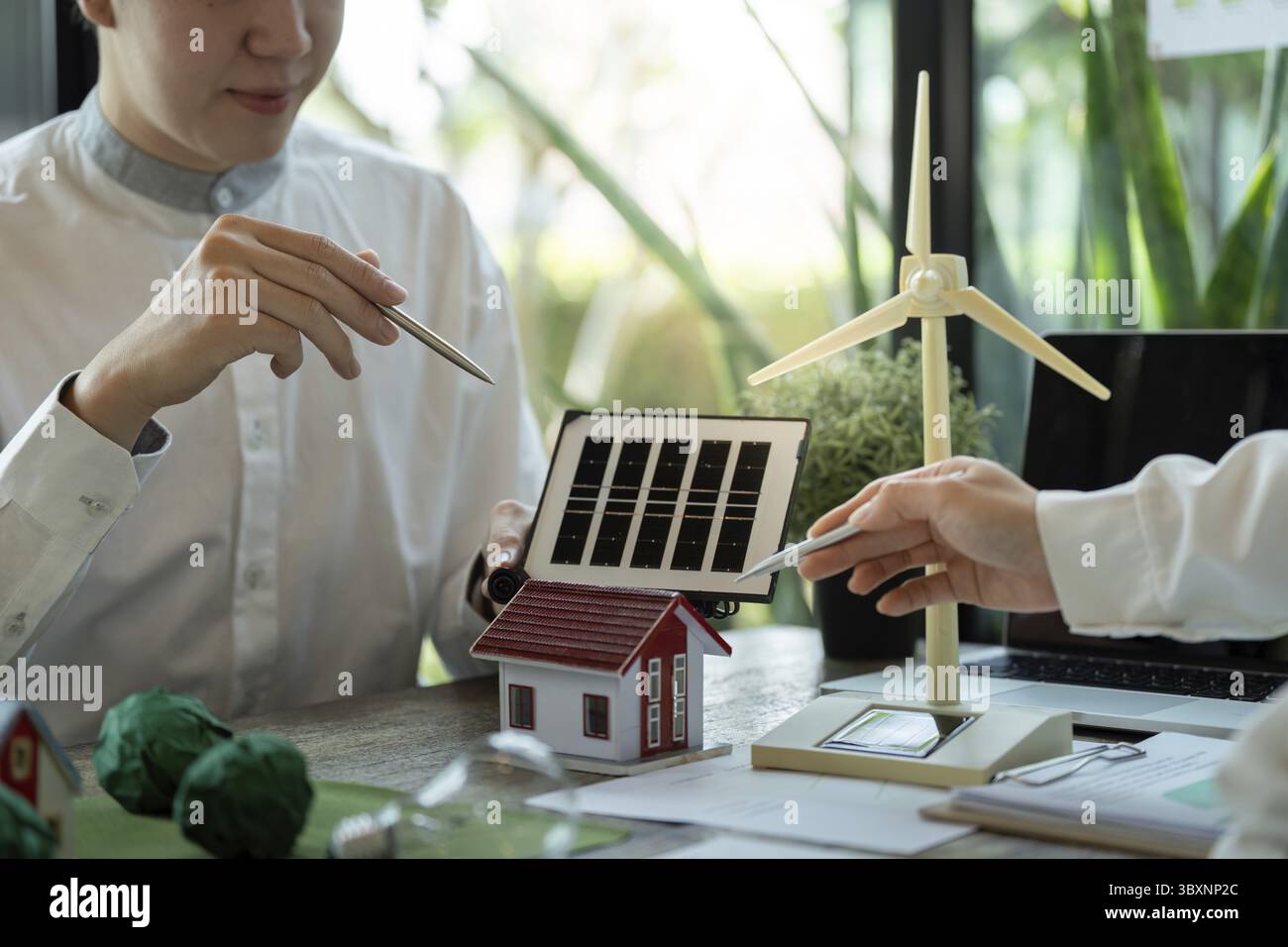 Un incontro strategico si concentra su soluzioni abitative ecocompatibili, con professionisti che esaminano come le tecnologie solari ed eoliche possono migliorare la sostenibilità Foto Stock