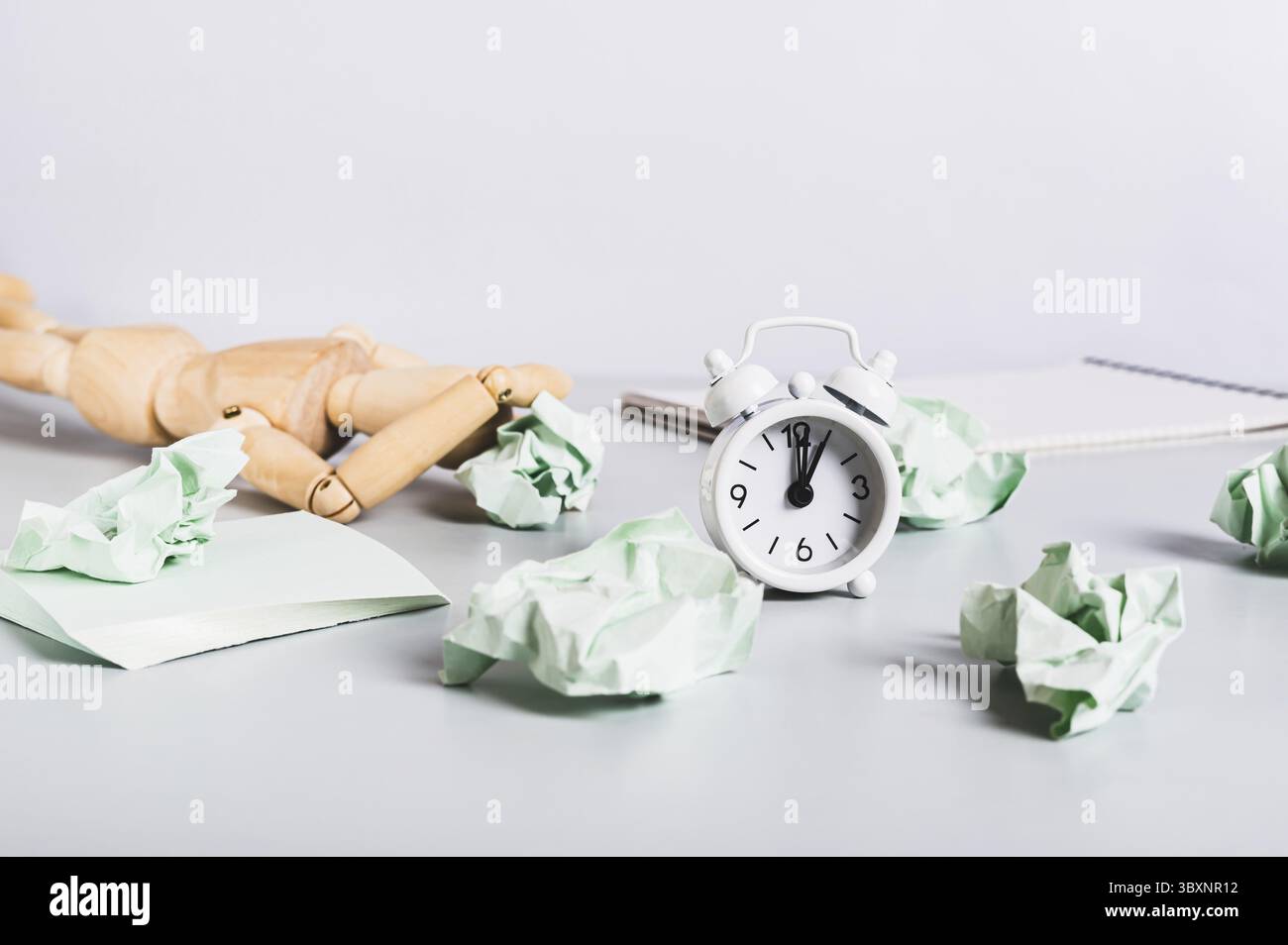 Cibo, uomo bruciato al lavoro, carta sguazzata, notebook e sveglia sulla scrivania Foto Stock