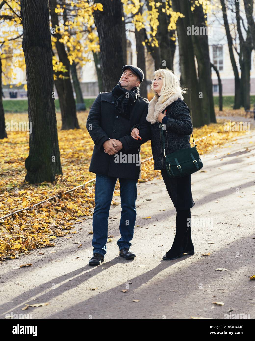 Felice donna bionda matura e bella bruna di mezza età, guardare fino al cielo, a piedi nel parco. Coppia amorevole di 45-50 anni passeggiate in autunno pa Foto Stock