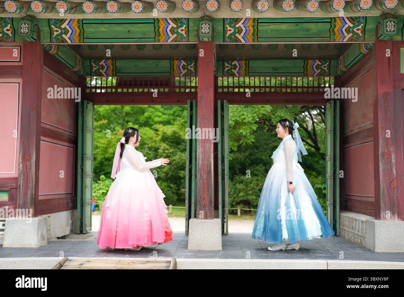 A giugno a Seul, due donne coreane sui vent'anni si stendono fianco a fianco davanti alla maestosa porta antica del Palazzo Gyeongbokgung, indossando l'affascinante spilla Foto Stock