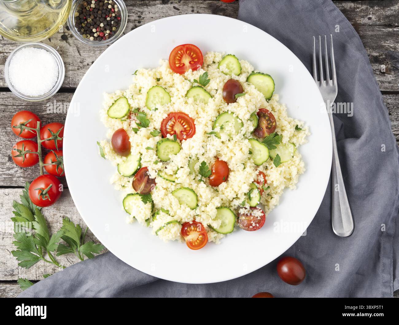 La dieta fresca insalata di verdure con cuscus, pomodori, cetrioli, prezzemolo, scuro tavola in legno rustico, vista dall'alto Foto Stock