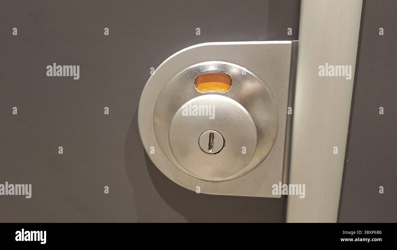 Fissare il meccanismo metallico della serratura della porta con un foro sulla superficie grigia Foto Stock