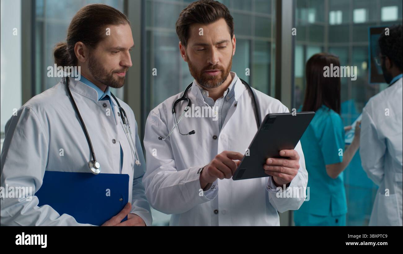 Esperto Caucasico due uomini medici medico chirurgo pediatra medico in grembiule stetoscopio che esamina il risultato del test di salute del paziente utilizzando Foto Stock