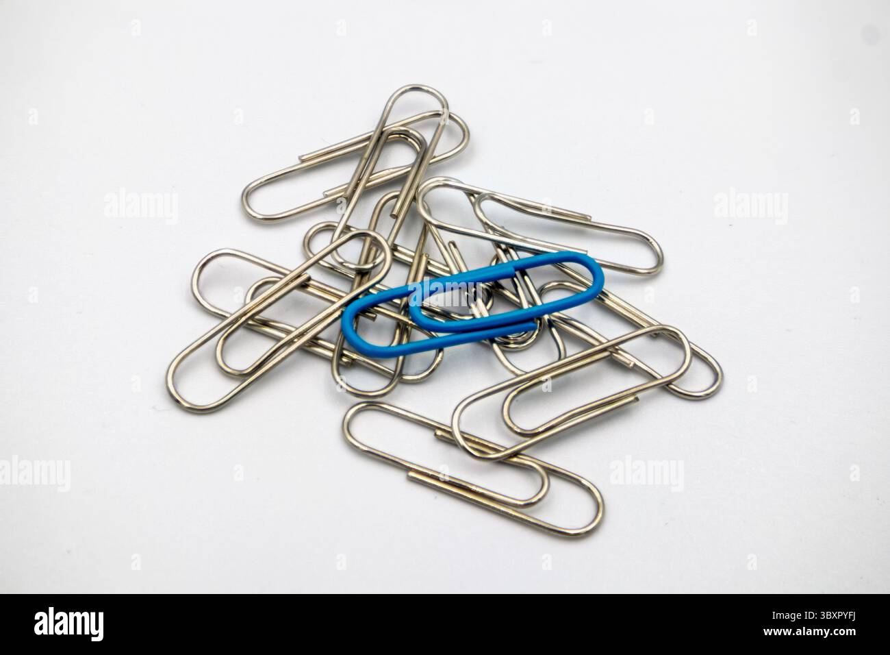 Un fermaglio di carta blu che si stacca da un mucchio di argento Foto Stock Un fermaglio di carta blu che si stacca da un mucchio di argento Foto Stock